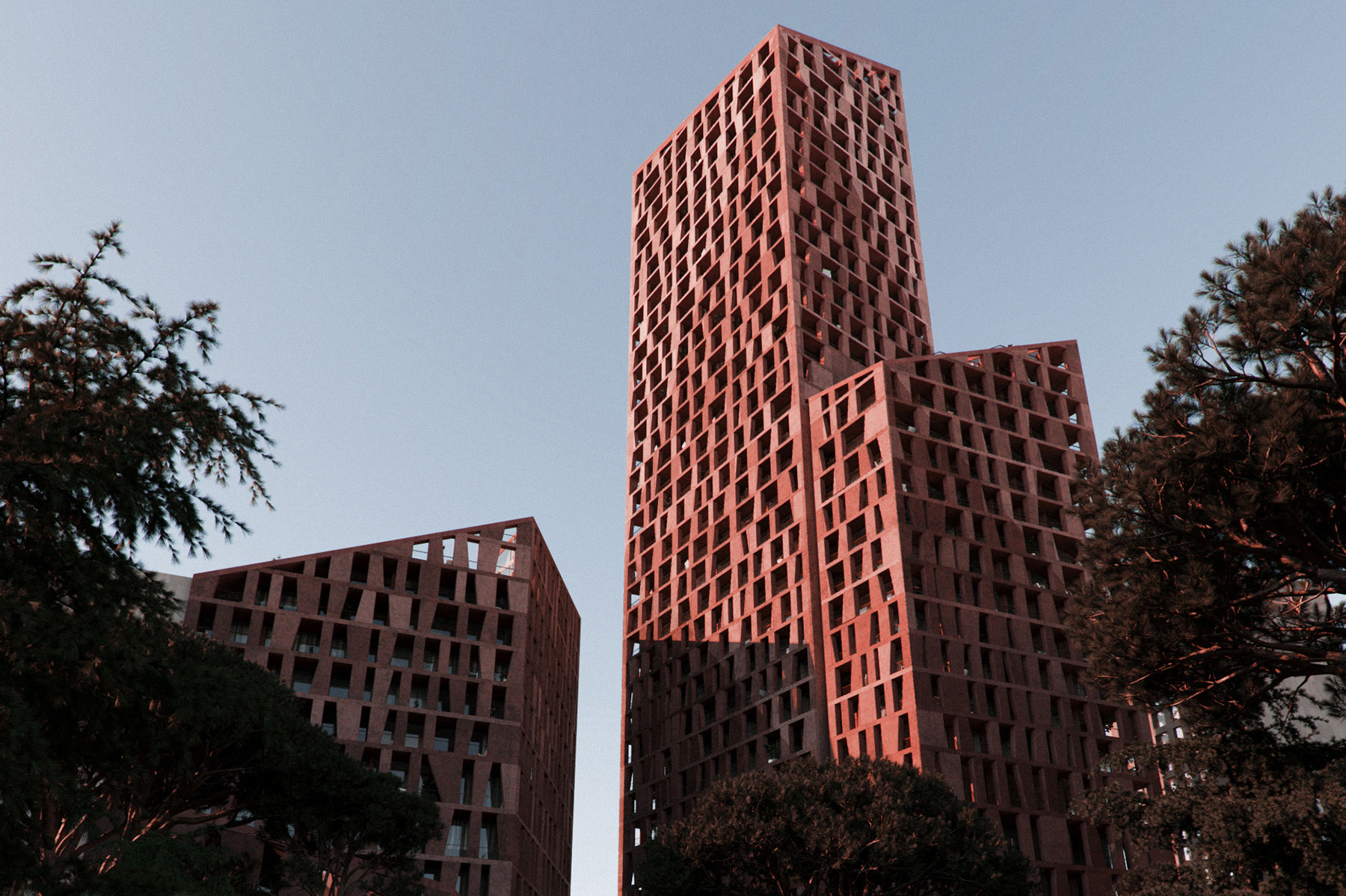 A rendering from a street-level view of a high-rise building with brown textured walls and differently shaped cutouts.