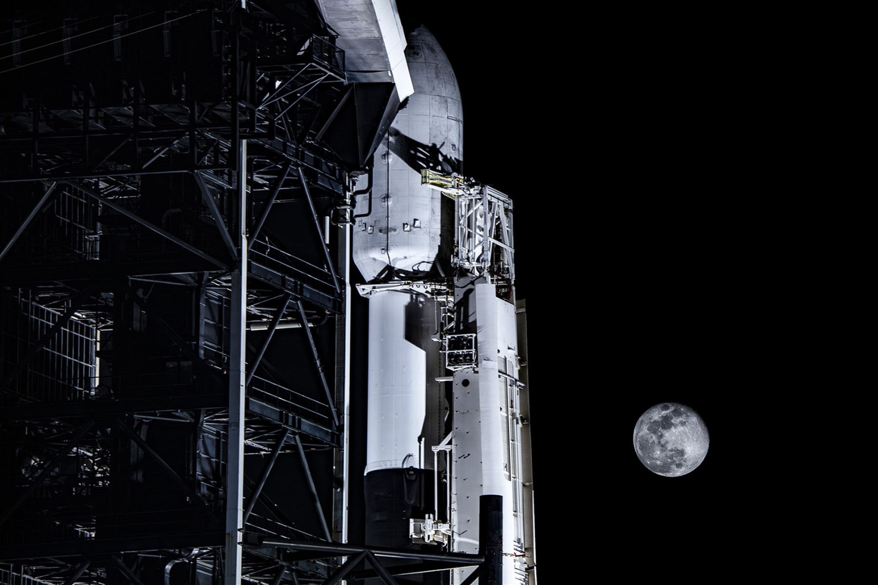 A rocket ship sits on its dock at nighttime.