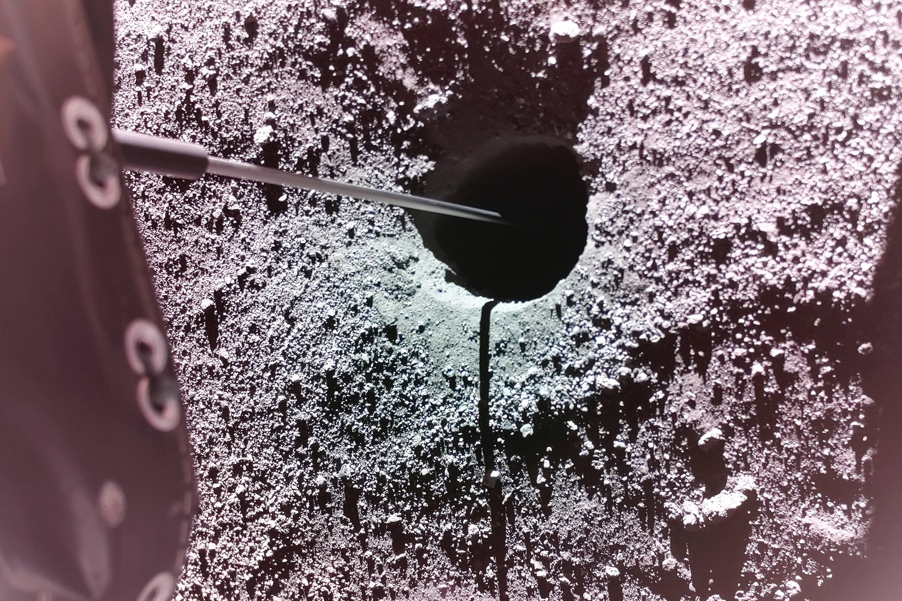 An up-close image of a small hole in the rocky, gravely gray surface of the moon.