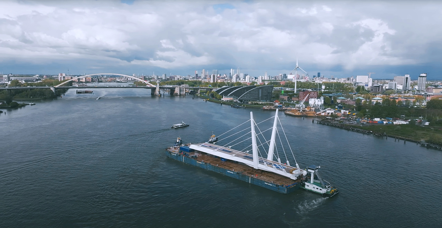 A leaf of a swing-span bridge is on a barge being floated to the construction site.