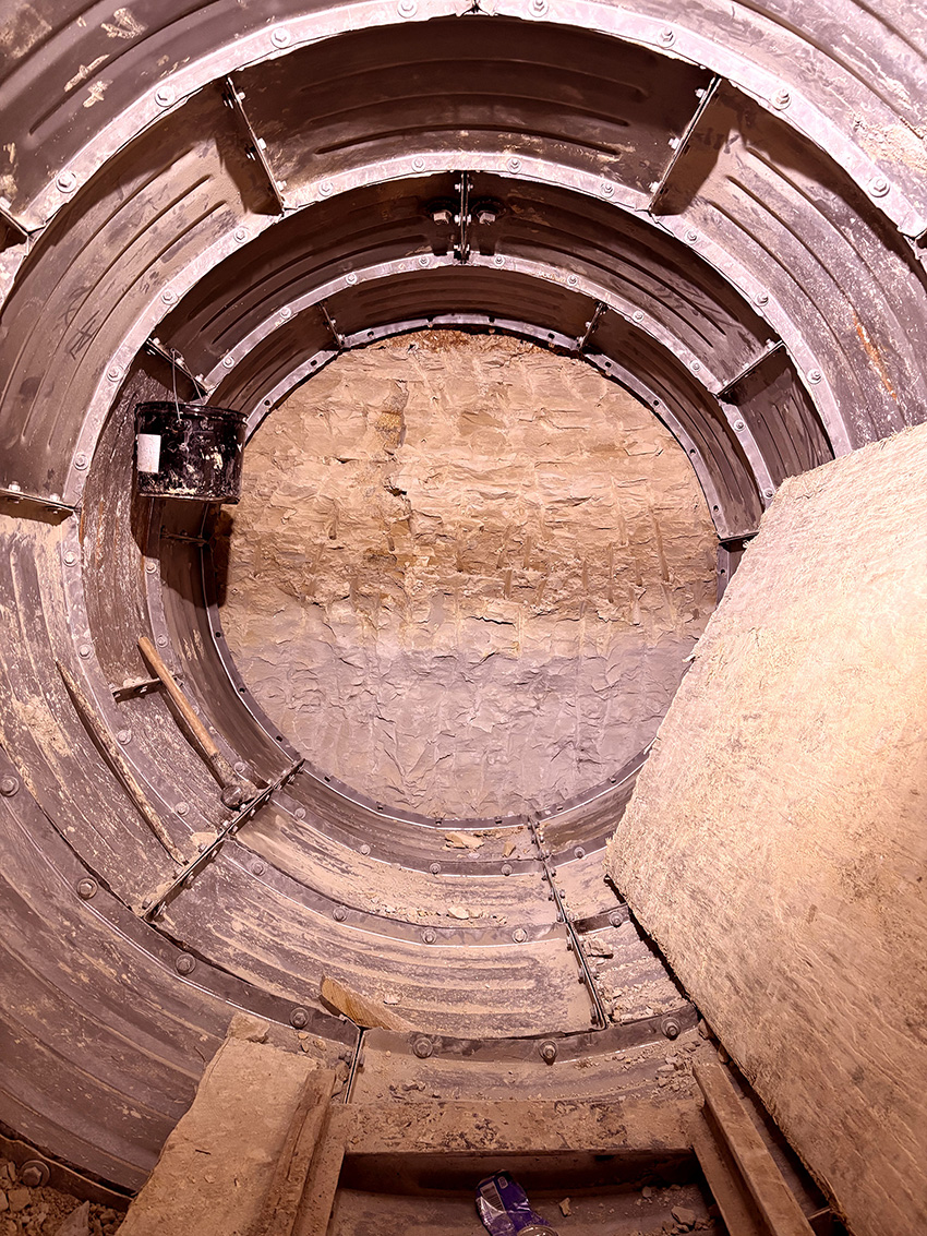 Photo shows the interior of a tunnel where contractors hand-mined through rock for a portion of an underground sewer project. 
