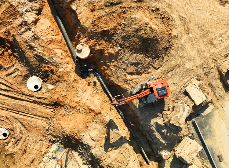 Photo shows the installation of a sewage drainage system at construction site. 
