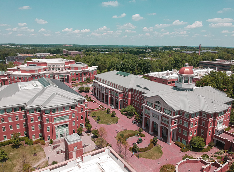 An aerial photograph shows major red-brick academic buildings at UNC Charlotte. 