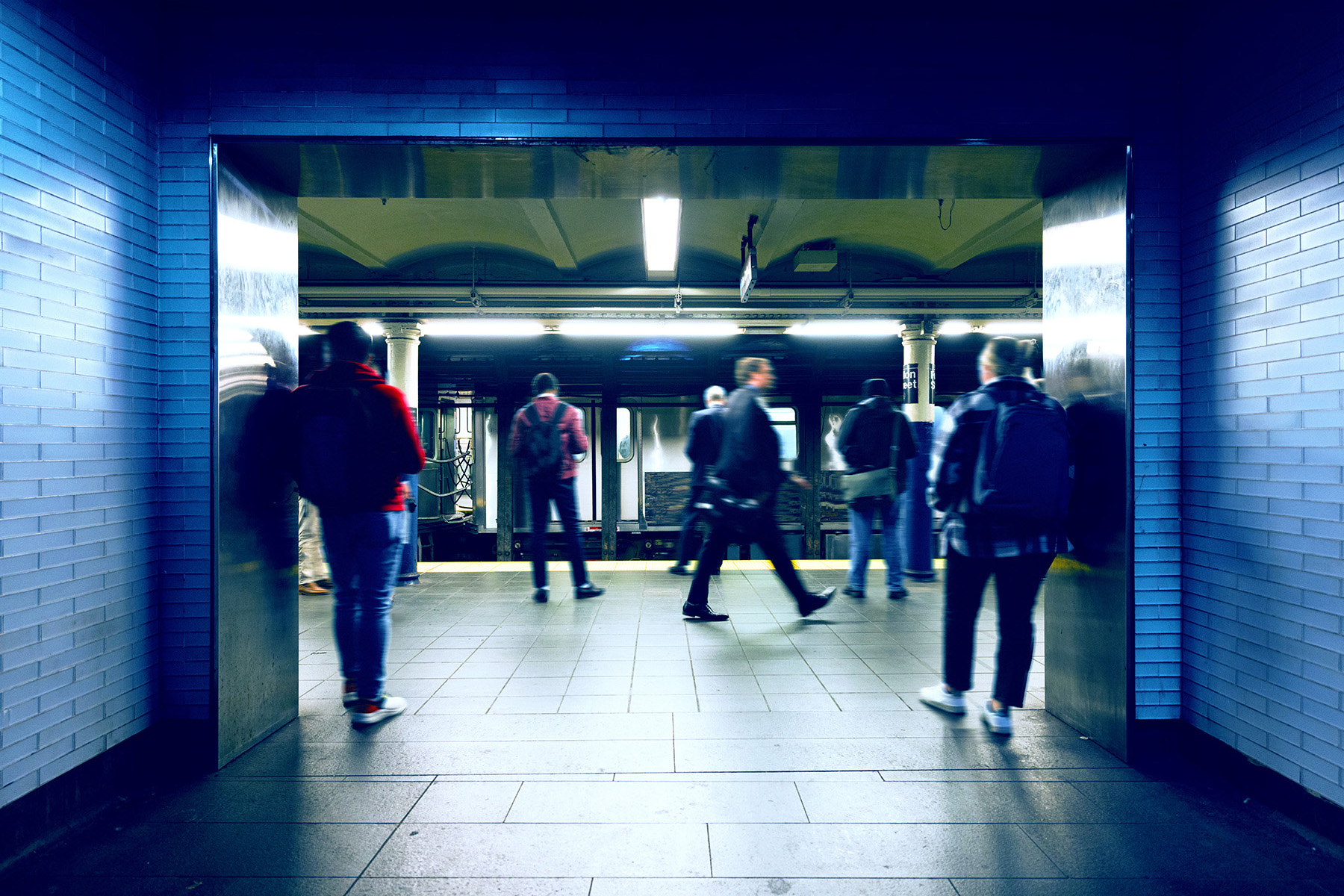 People stand waiting on a platform of a subway station in New York City. 
