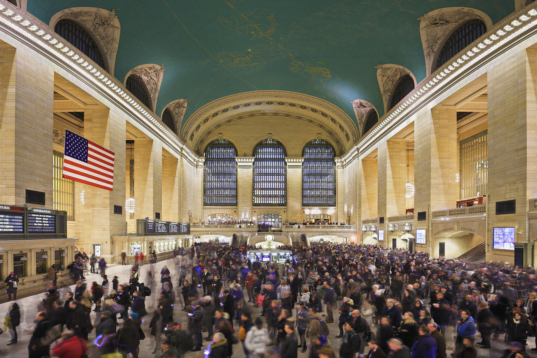 A blurry crowd of people walk through Grand Central Station.
