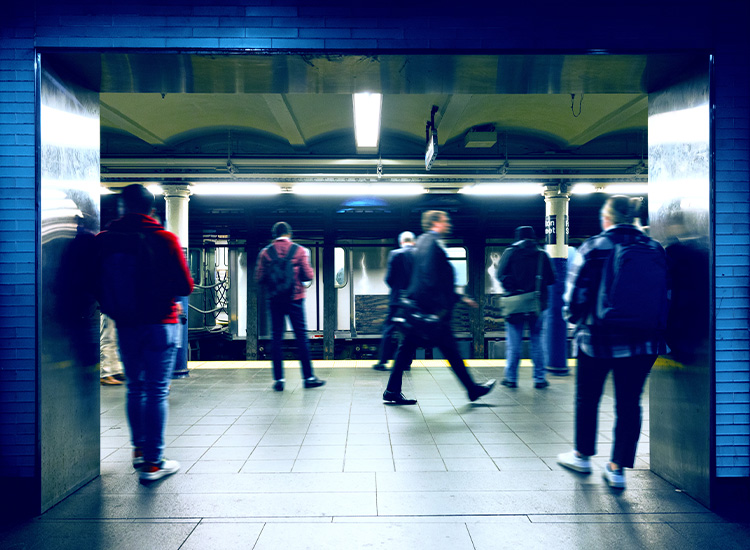 People stand waiting on a platform of a subway station in New York City.