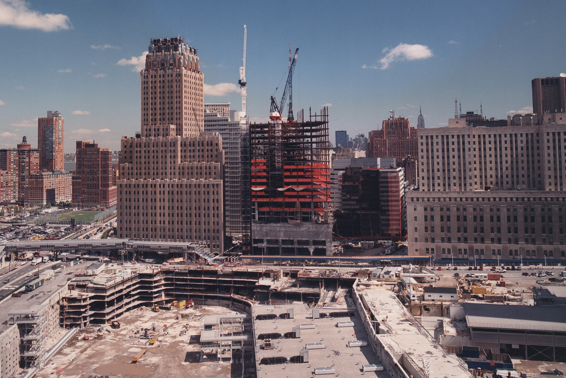 Photograph shows the construction of a tall building. In the foreground is the foundation of another supertall building.