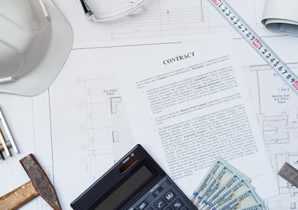 Blueprints, contract on a desk with hardhat, calculator and money