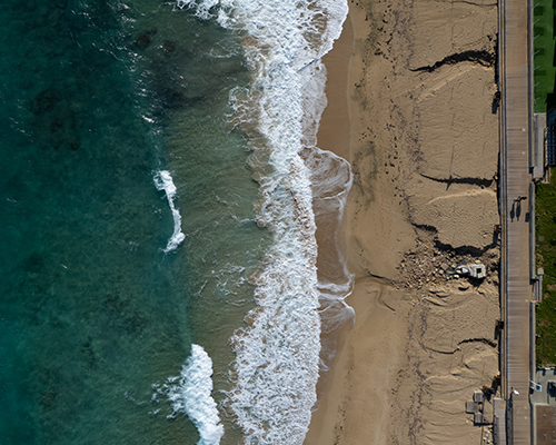 Aerial view of ocean waves breaking on a sandy beach