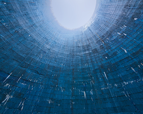 A low angle futuristic shot of a blue cooling tower showing brick structure