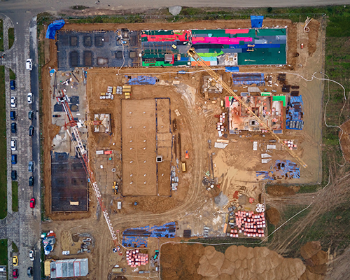 Aerial view of construction site with building materials stacked around two structures under construction