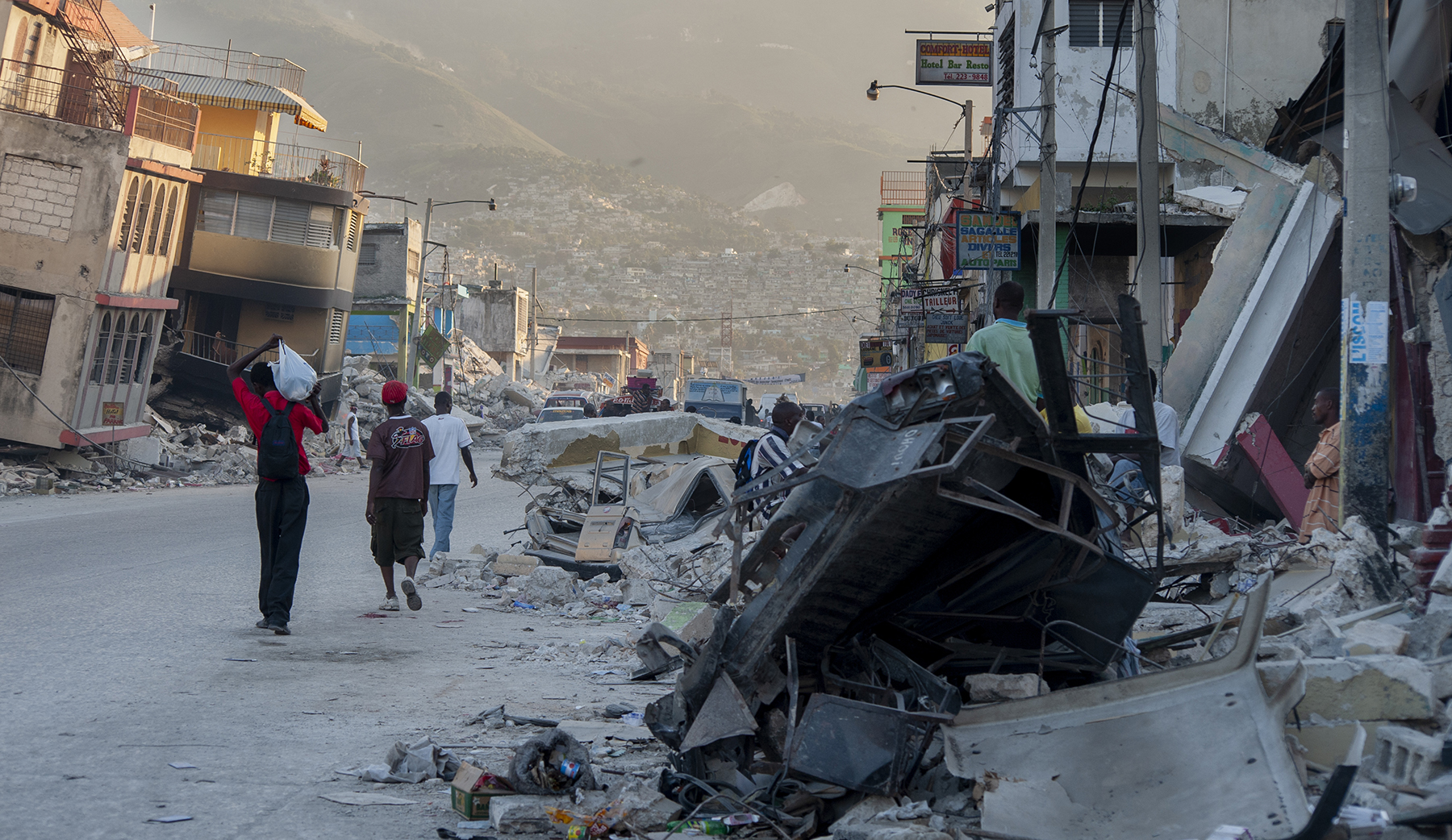 people walk on a street filled with earthquake devastation people walk on a street filled with earthquake devastation