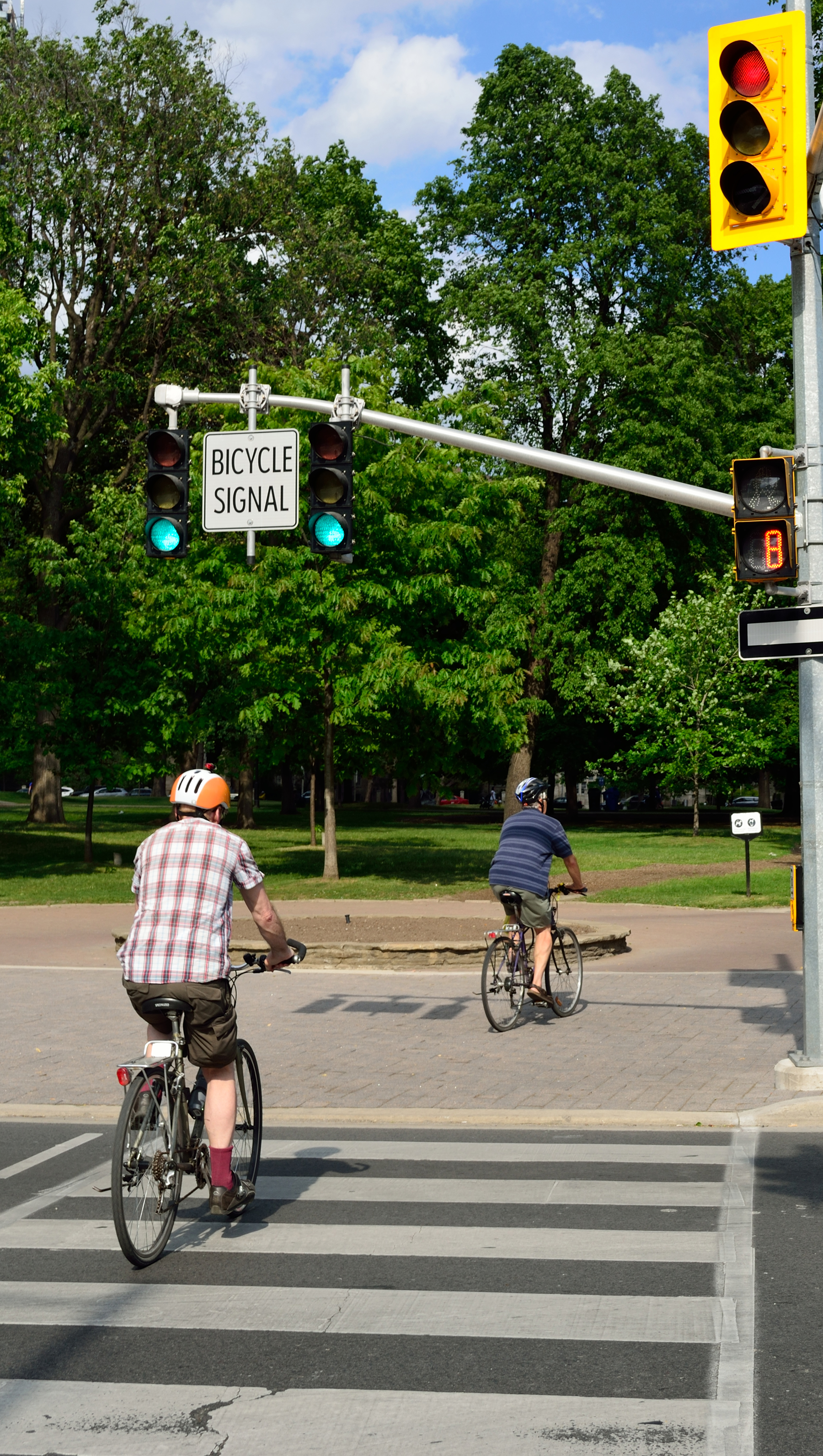two cyclists cross a street in a crosswalk two cyclists cross a street in a crosswalk