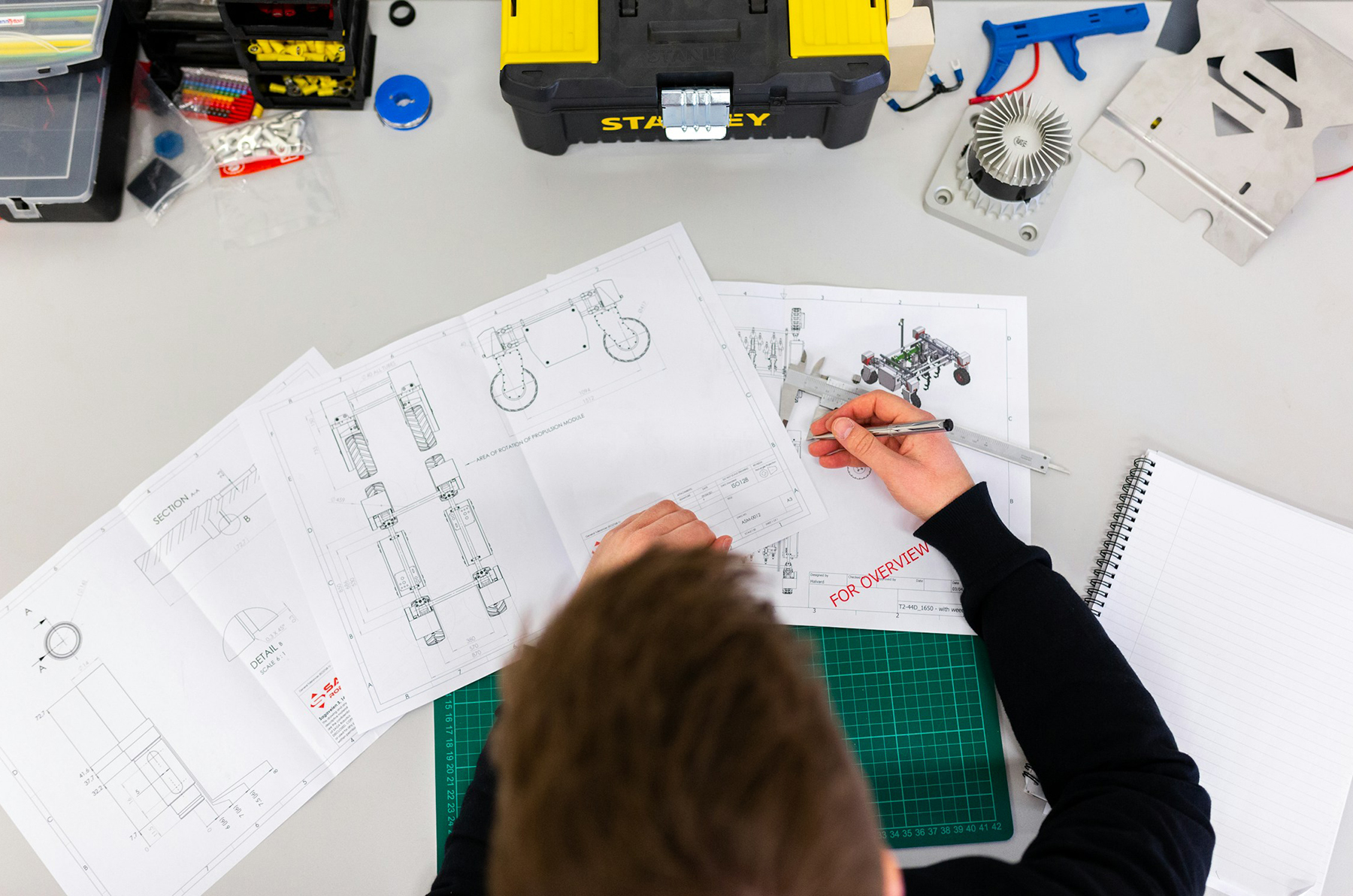 overhead shot of person at a desk covered with engineering-related items 