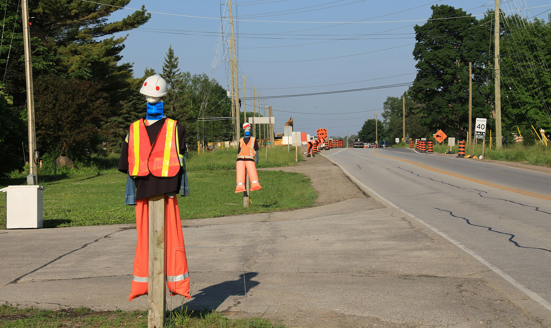 wooden poles are decoated with construction workers hard hats and vests along a road