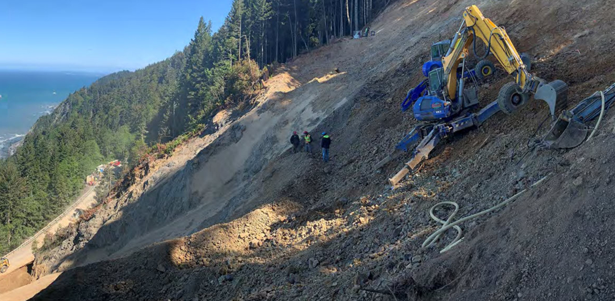a crane and a crew work in rough, sloping terrain
