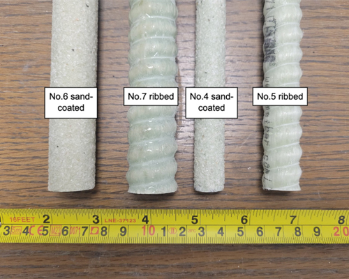 Four sand coated pipes of various sizes on a desk top with a measuring tape at the bottom of the image.