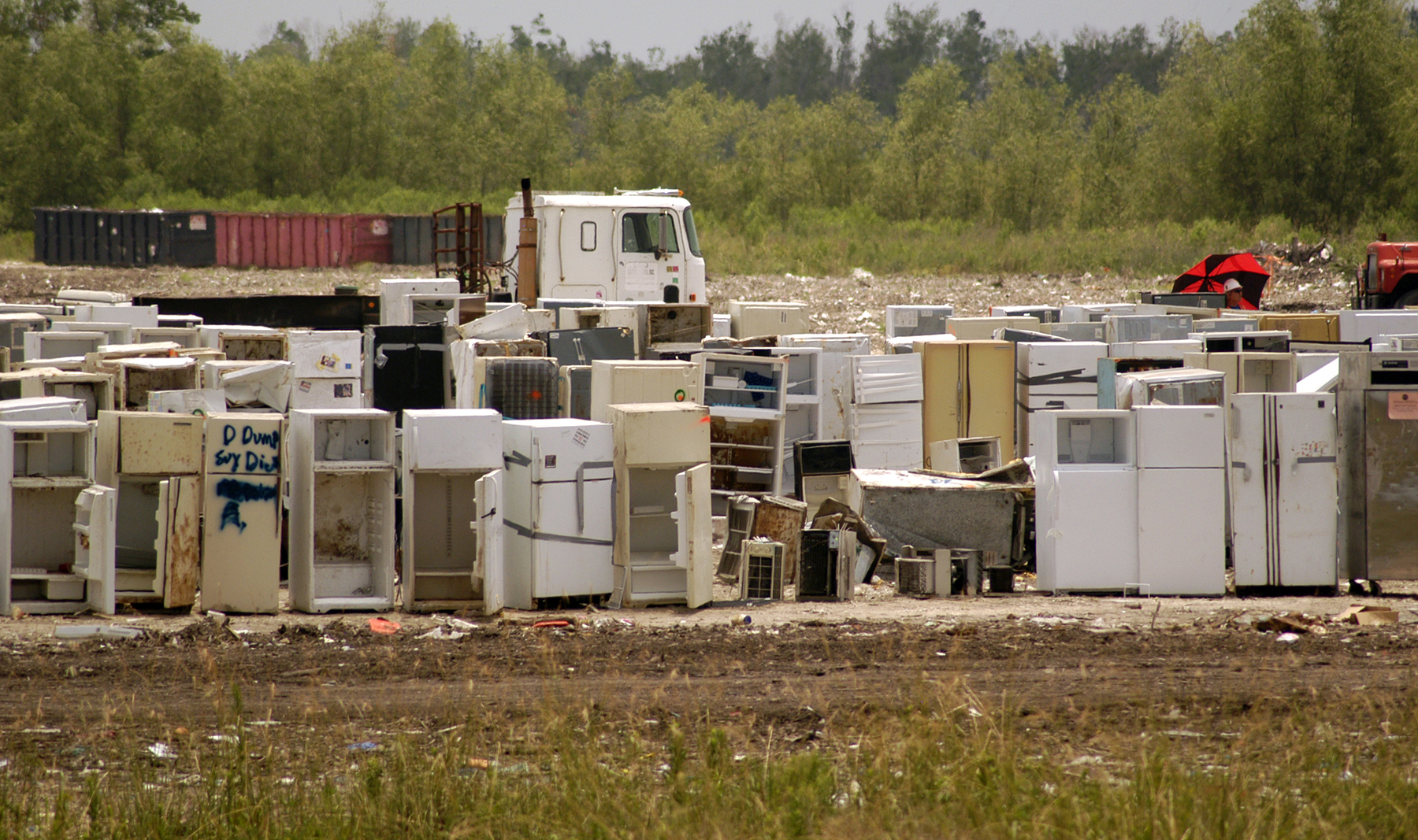 old refrigerators line a field with a truck in the background old refrigerators line a field with a truck in the background