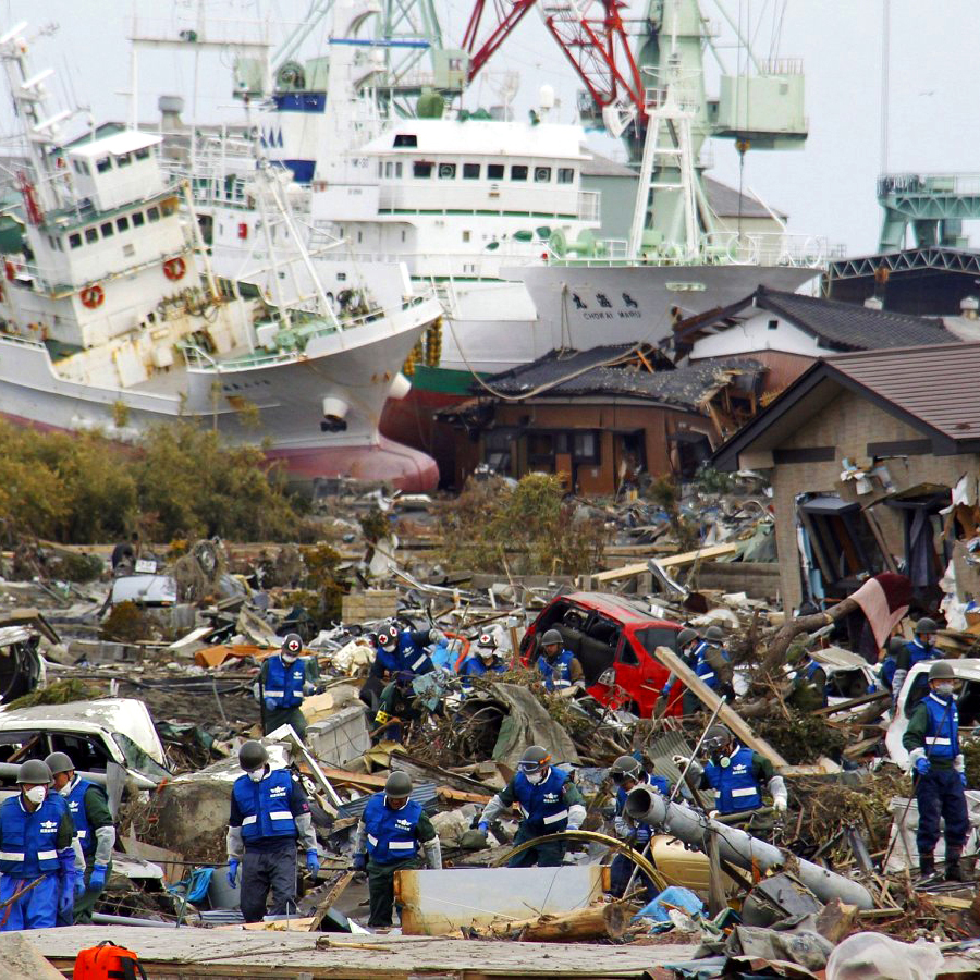 crews work on removing debris with two ships in the background