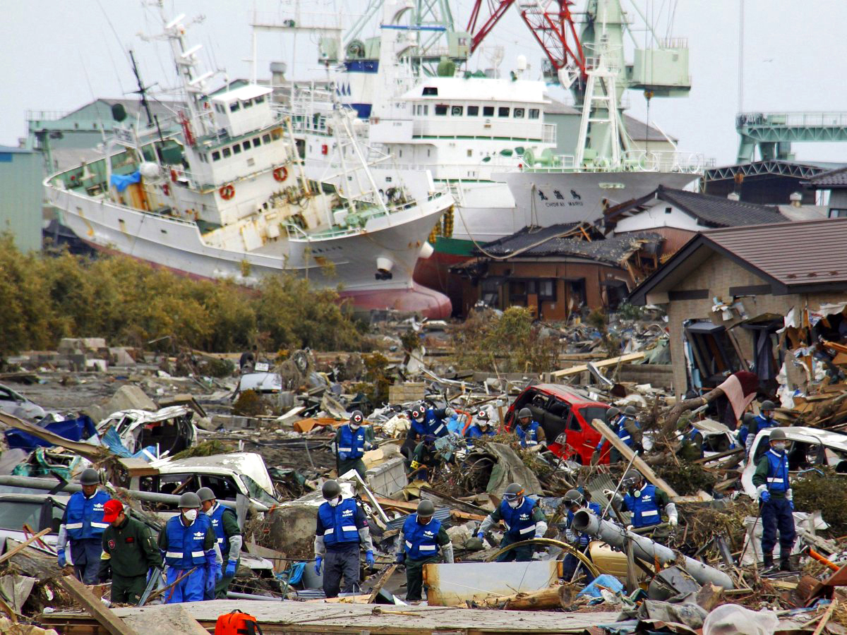 workers clear mounds of debris with two ships in the background workers clear mounds of debris with two ships in the background