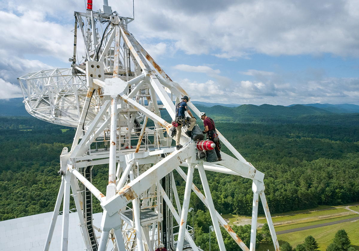 people work on the giant telescope with a mountainous background people work on the giant telescope with a mountainous background