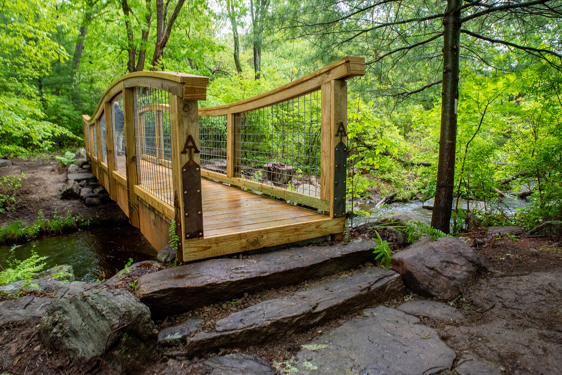 image of a wooden pedestrian bridge spanning water image of a wooden pedestrian bridge spanning water
