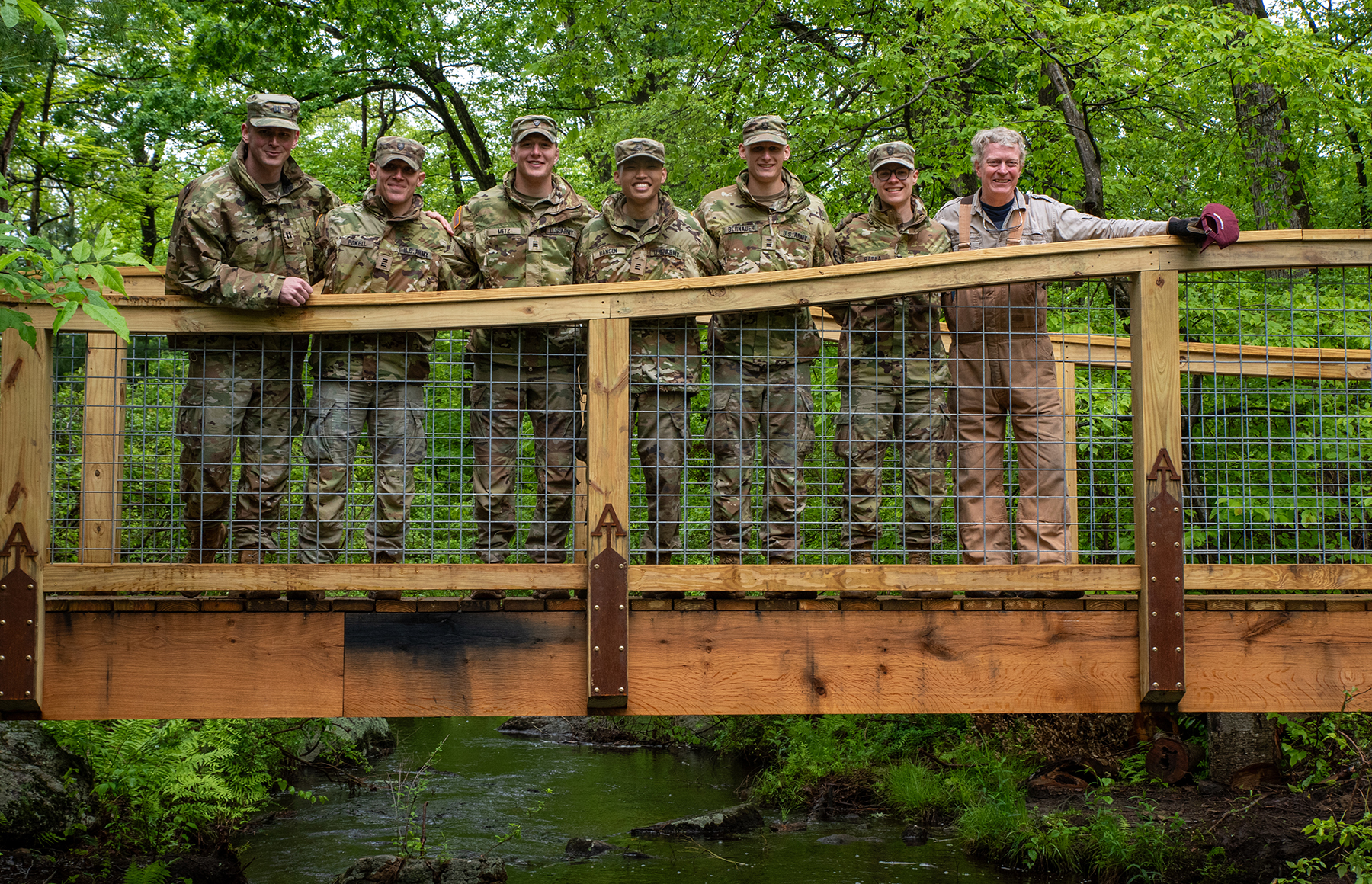 a group of people stand on a pedestrian bridge and smile for the camera a group of people stand on a pedestrian bridge and smile for the camera