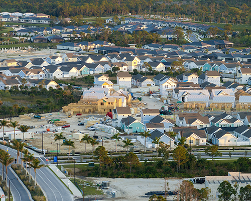 Aerial view of housing development with finished and unfinished homes and highway on lower left of image