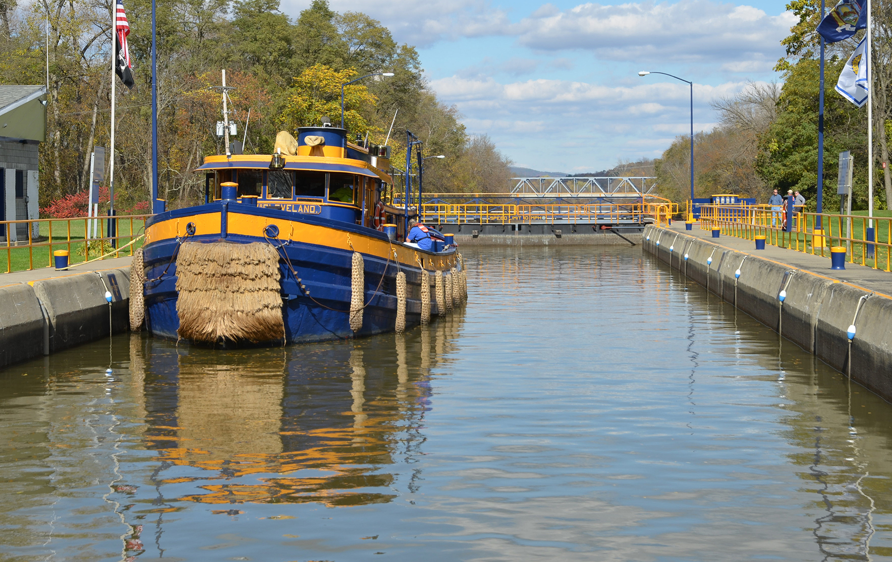 a blue and yellow tugboat sits in a lock in the Erie Canal a blue and yellow tugboat sits in a lock in the Erie Canal