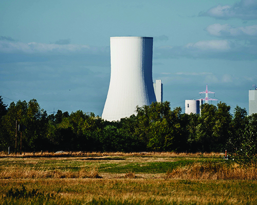 Nuclear power plant with blue sky and a field in the foreground