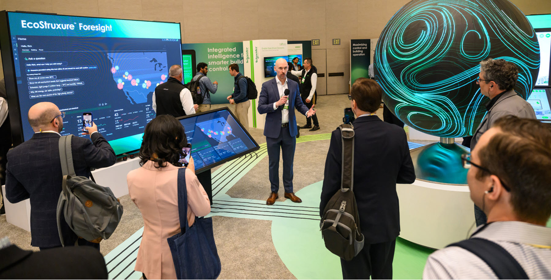 a person with a microphone is the center of attention in a crowd with an orb-like fixture in the right of the frame