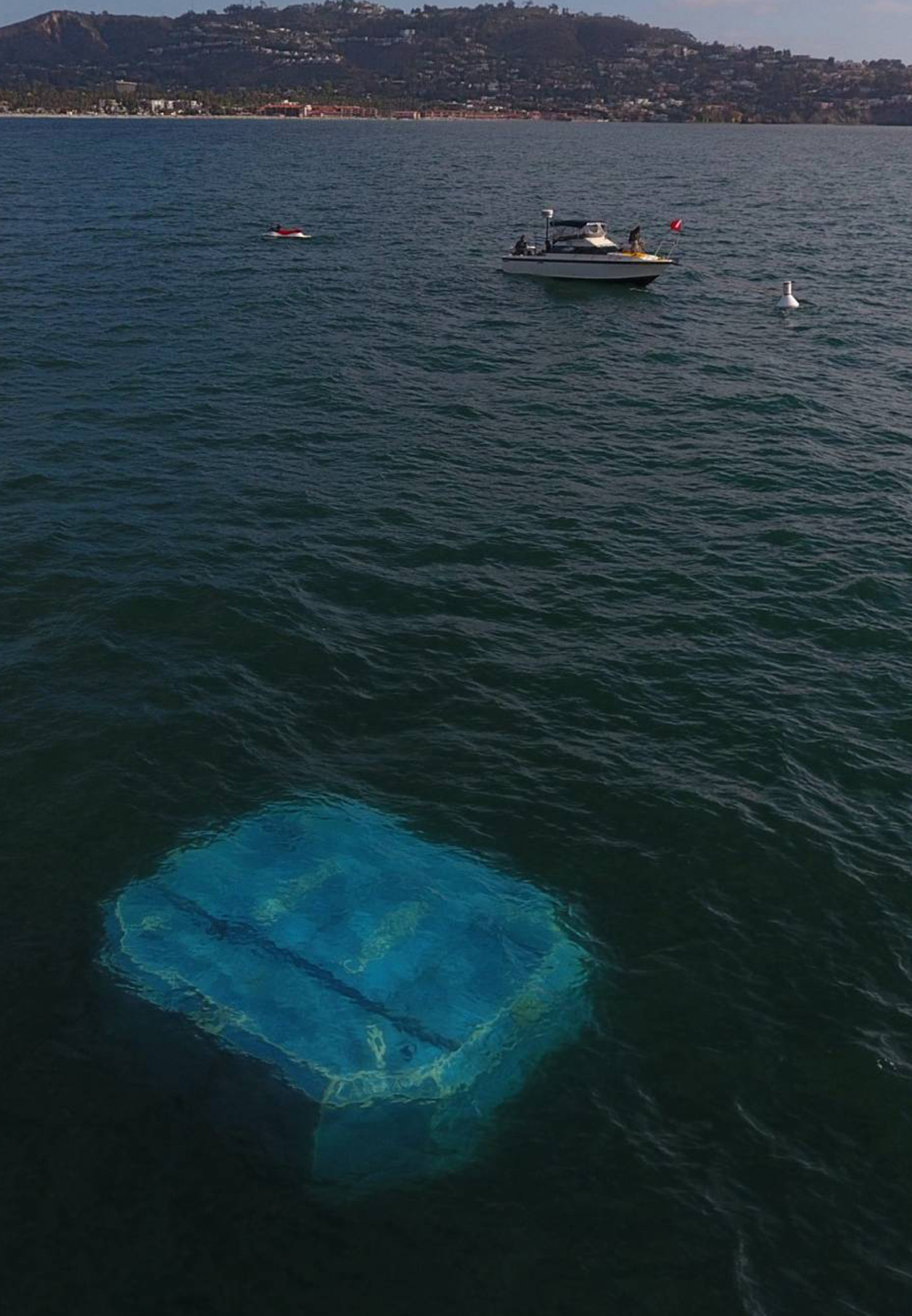 a blue object floats near the surface in the water with a boat in the foreground