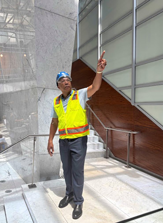 a man in a yellow vest stands on a staircase and points upward