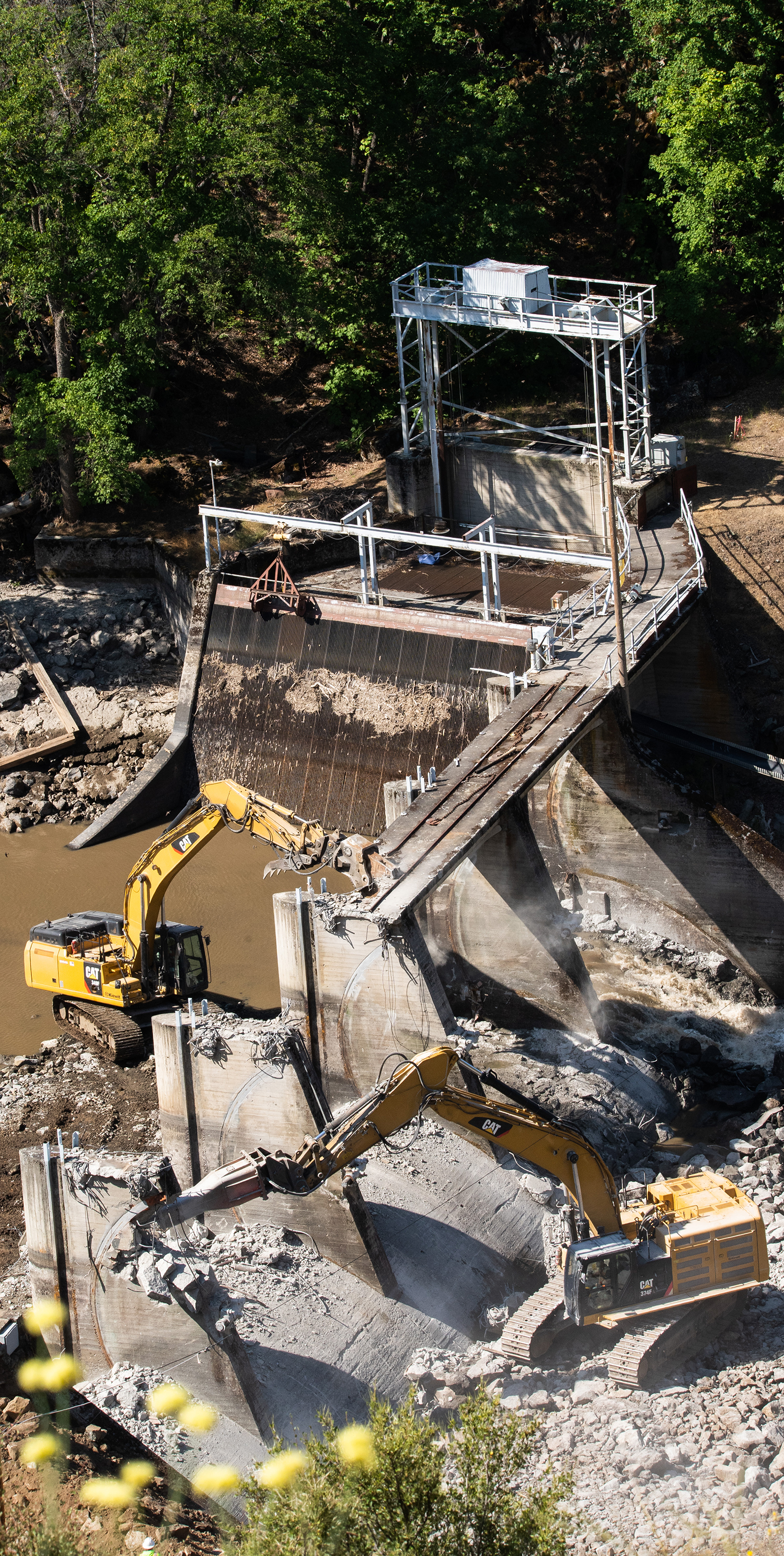 excavators dismantle the remaining structure of a dam