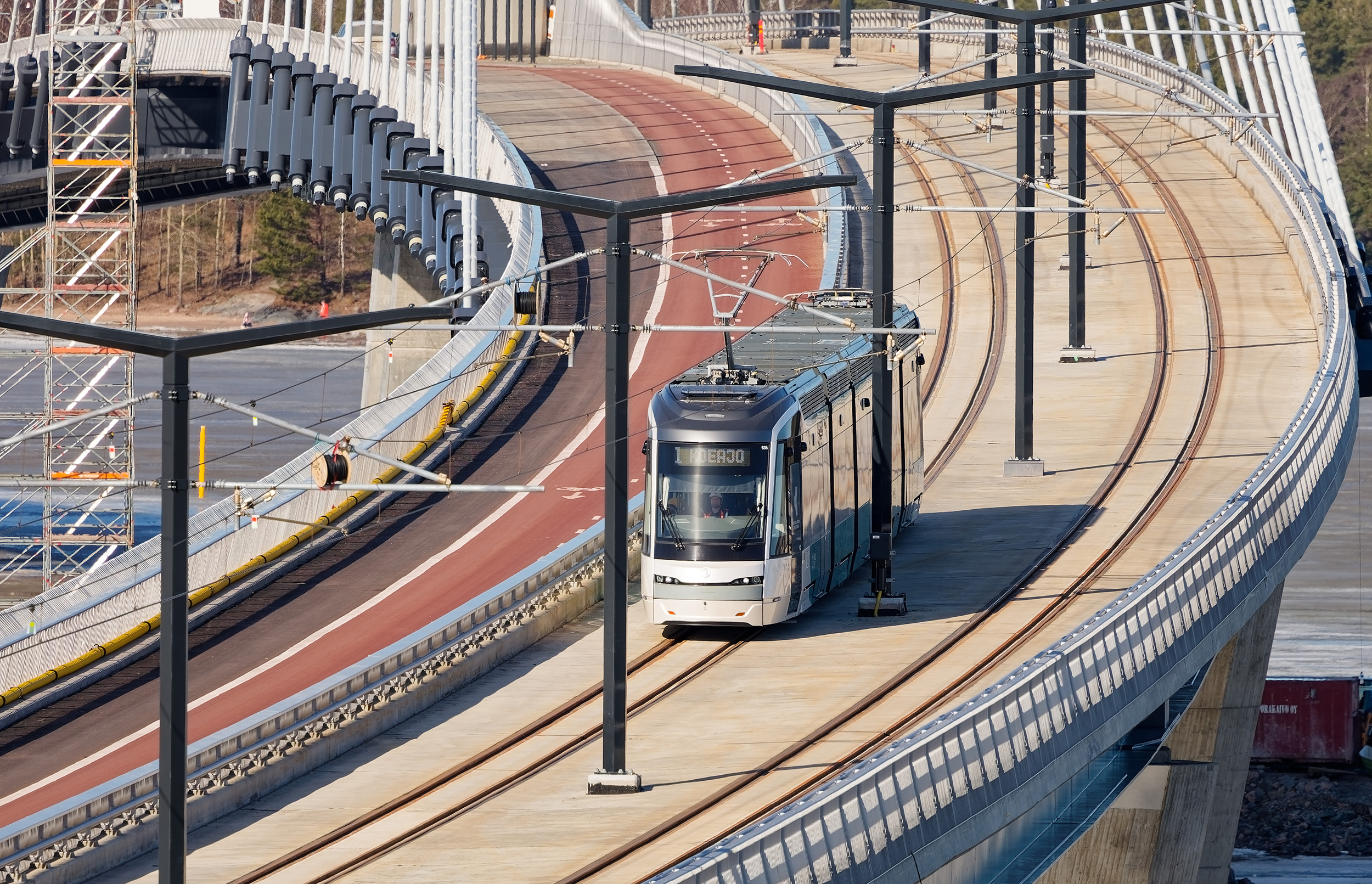 A modern tram travels along tracks on a bridge 