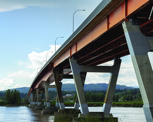 A low-angle shot of concrete & steel composite bridge and body of water