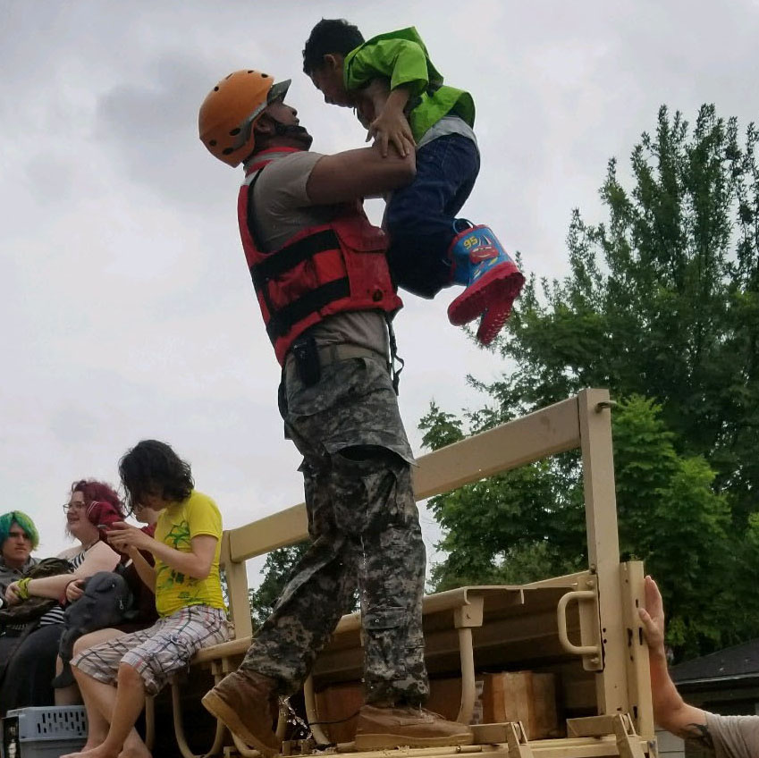 Emergency responder assisting child during flood rescue
