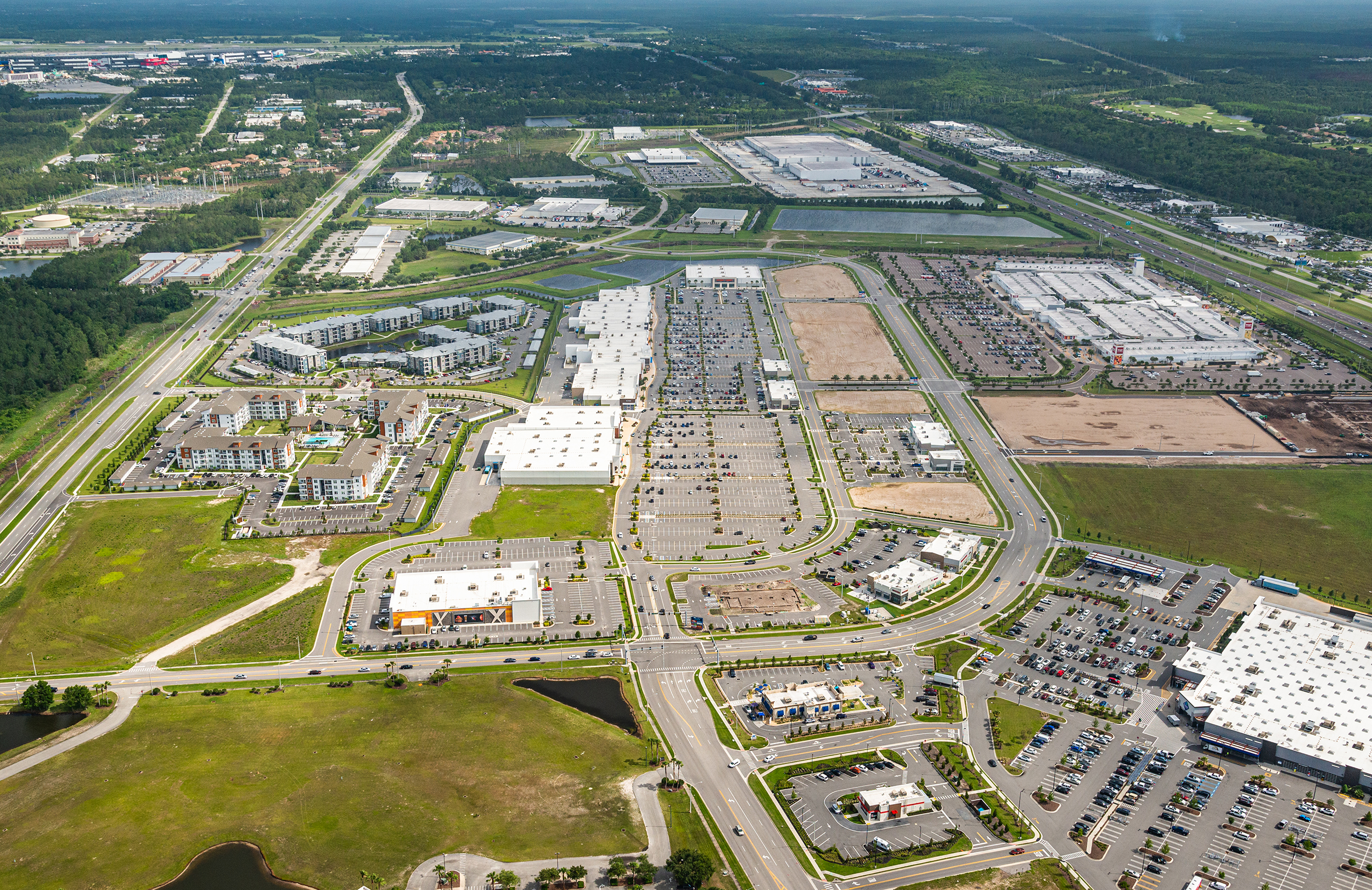 Aerial view of suburban shopping centers, roads, parking lots, and housing development
