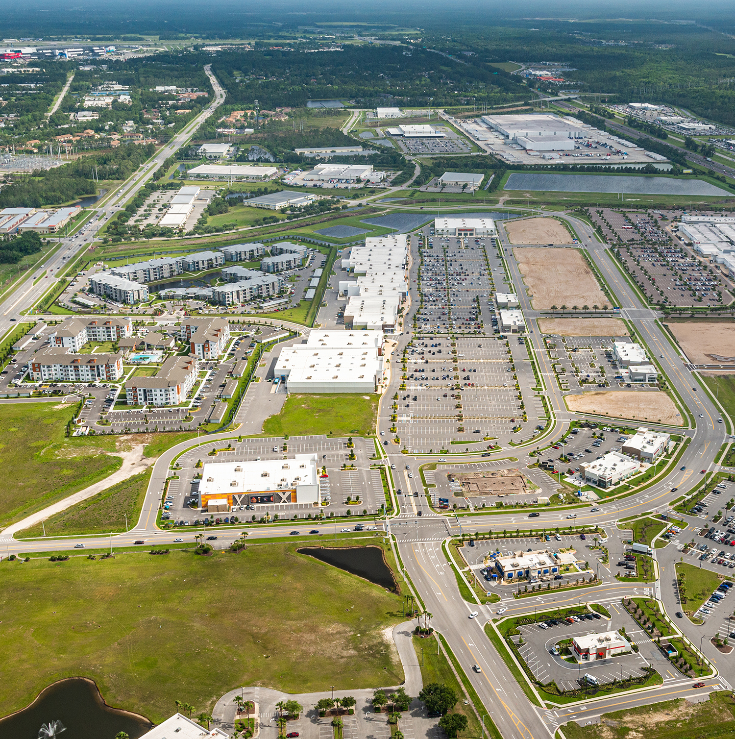 Aerial view of suburban shopping centers, roads, parking lots, and housing development