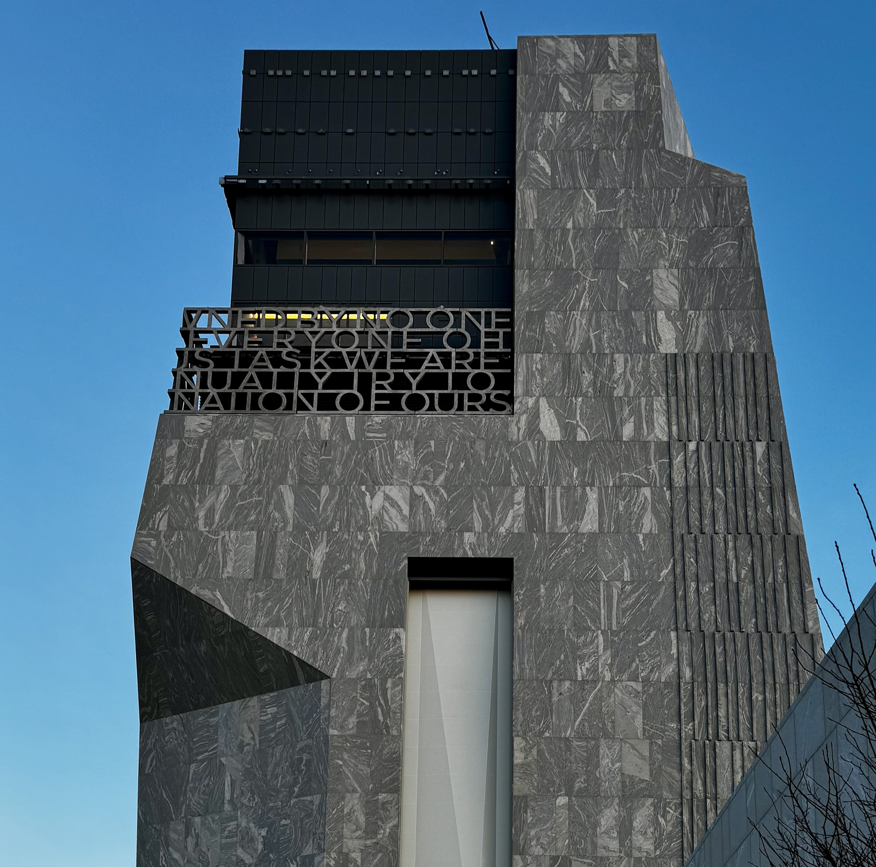 Tall marble-clad Obama Presidential Center tower with inspirational quote facade