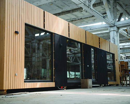 A completed modular home stands ready for transport in a construction workshop