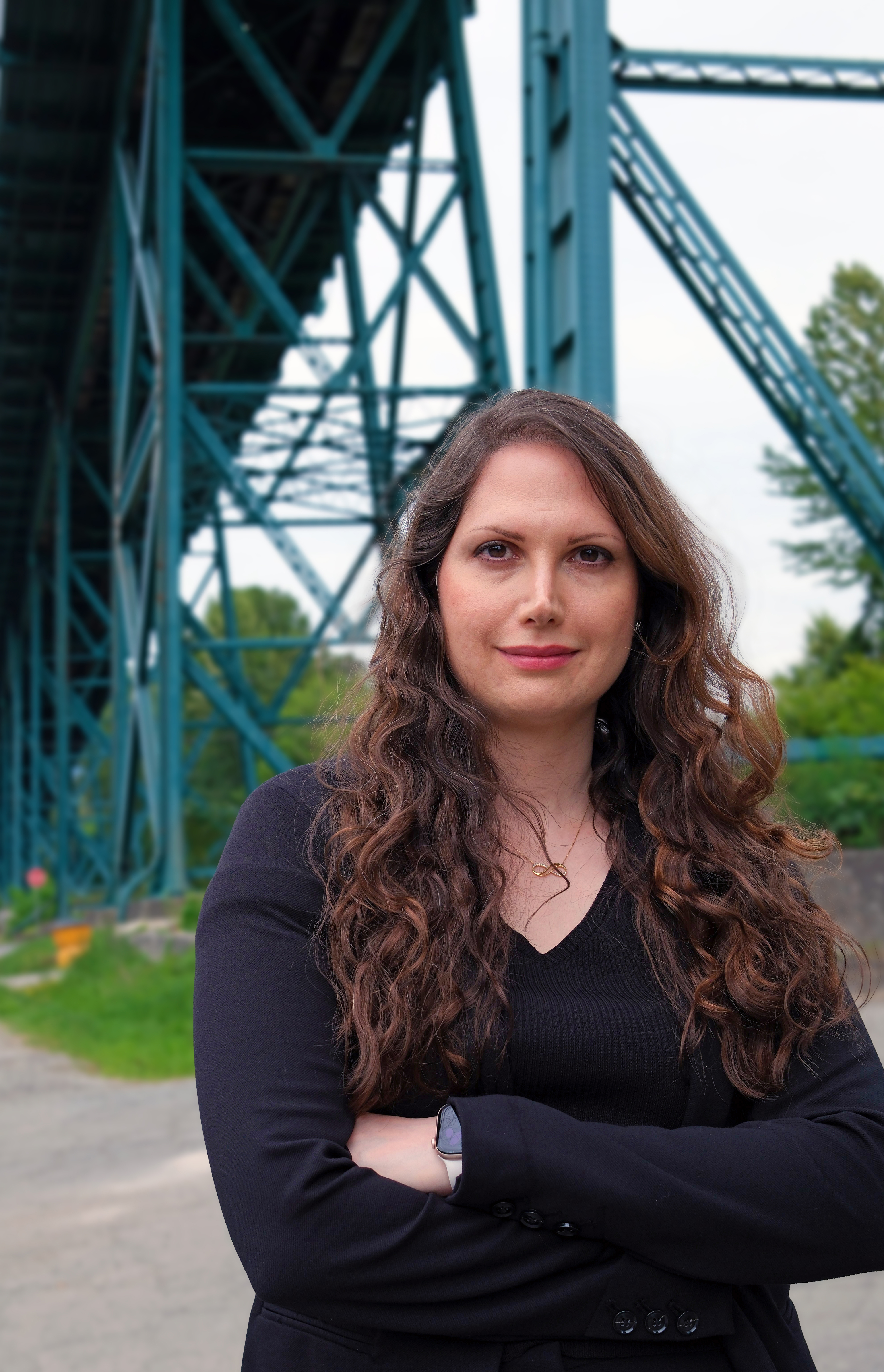 A woman standing beneath a steel truss bridge