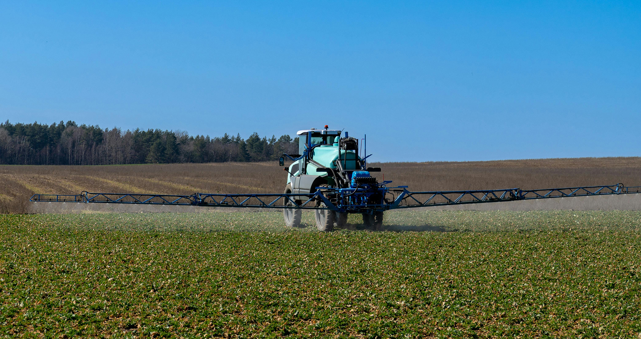 Agricultural sprayer applies fertilizer across a cultivated field