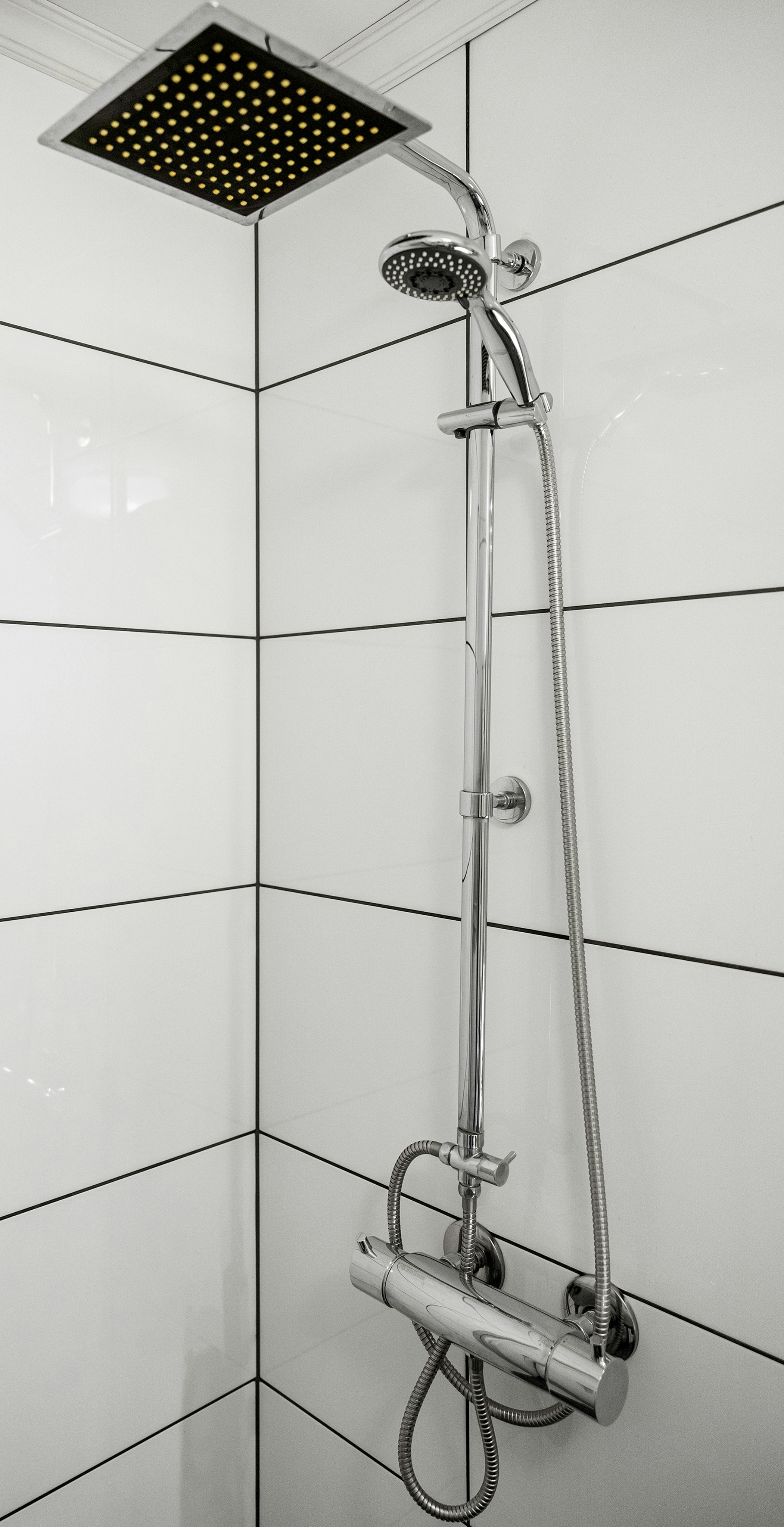 Water-efficient shower fixture installed in a tiled residential bathroom