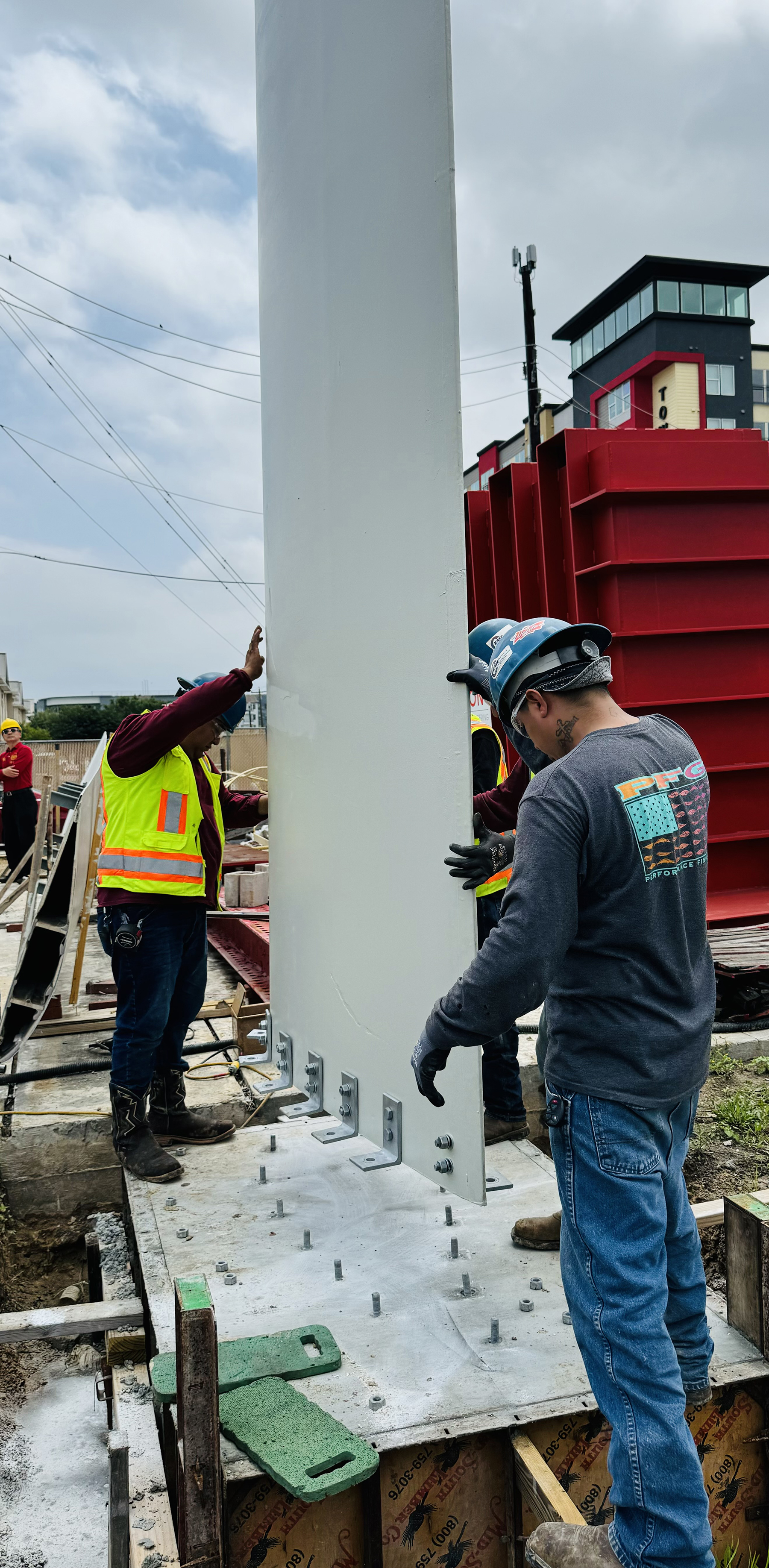 Workers install repurposed wind turbine blade segment on concrete foundation