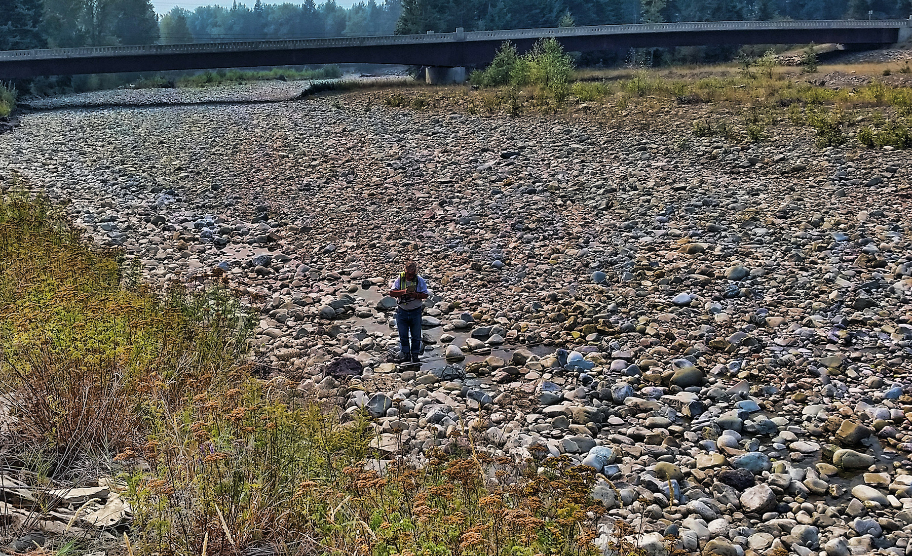 Technician measures streamflow in rocky creek channel