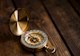 A golden compass rests on a hardwood floor, Credit: Aaron Burden